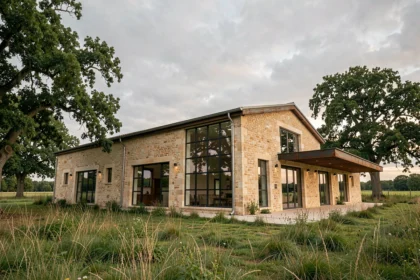 Extérieur d'une grange en pierre rénovée en maison moderne avec grandes fenêtres industrielles et extension contemporaine en zone rurale